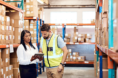 Buy stock photo Shot of a man and a woman using a digital tablet while working together in a warehouse