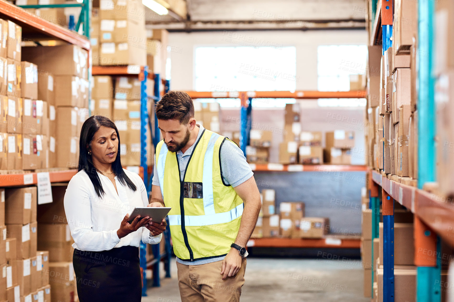 Buy stock photo Shot of a man and a woman using a digital tablet while working together in a warehouse
