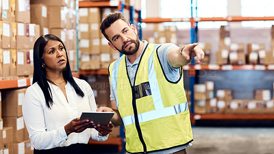 Buy stock photo Shot of a man and a woman using a digital tablet while working together in a warehouse