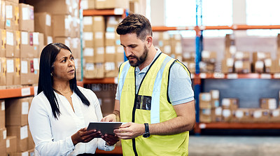 Buy stock photo Shot of a man and a woman using a digital tablet while working together in a warehouse