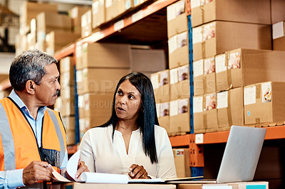 Buy stock photo Shot of a mature man and woman going through paperwork together in a warehouse