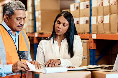 Buy stock photo Shot of a mature man and woman going through paperwork together in a warehouse