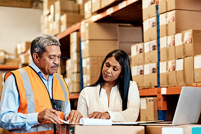 Buy stock photo Shot of a mature man and woman going through paperwork together in a warehouse