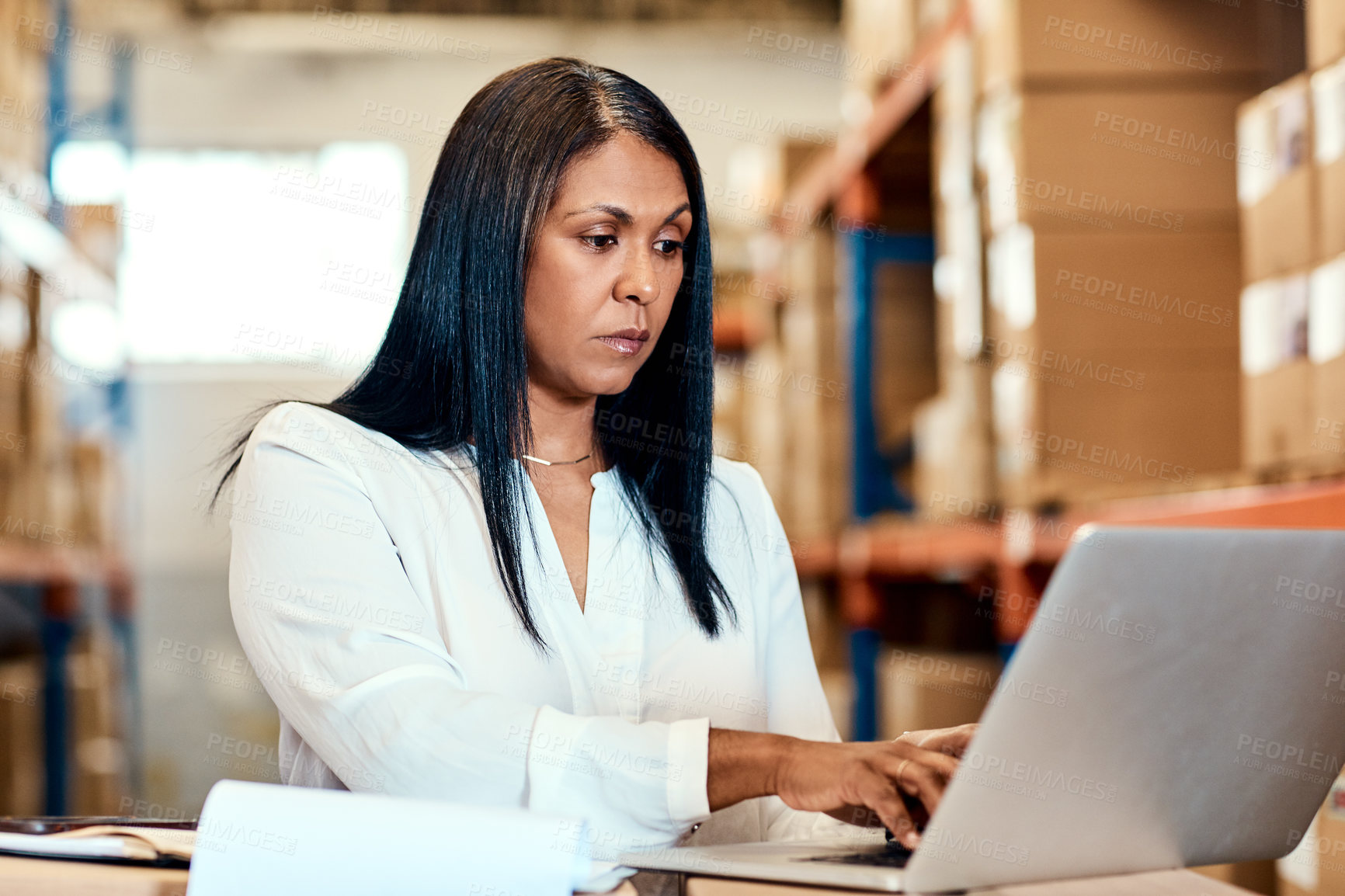 Buy stock photo Shot of a mature factory manager working on a laptop in a warehouse