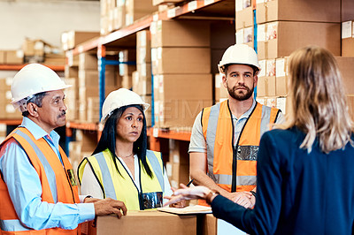 Buy stock photo Shot of factory workers having a discussion with the manager in a warehouse