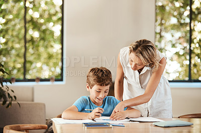Buy stock photo Shot of a cute little boy doing homework with his mother at home