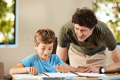 Buy stock photo Shot of a cute little boy doing homework with his father at home