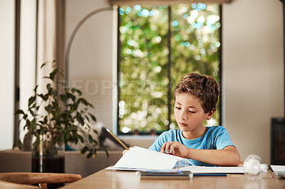 Buy stock photo Shot of a cute little boy doing his homework at home