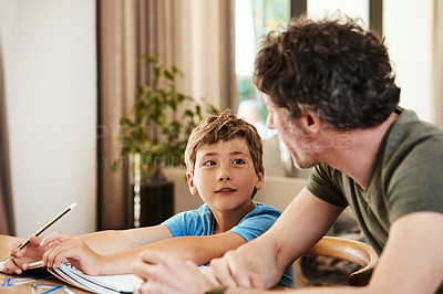 Buy stock photo Shot of a cute little boy doing homework with his father at home