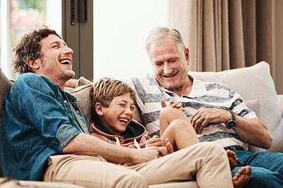 Buy stock photo Shot of an adorable little boy relaxing on the sofa with his father and grandfather at home