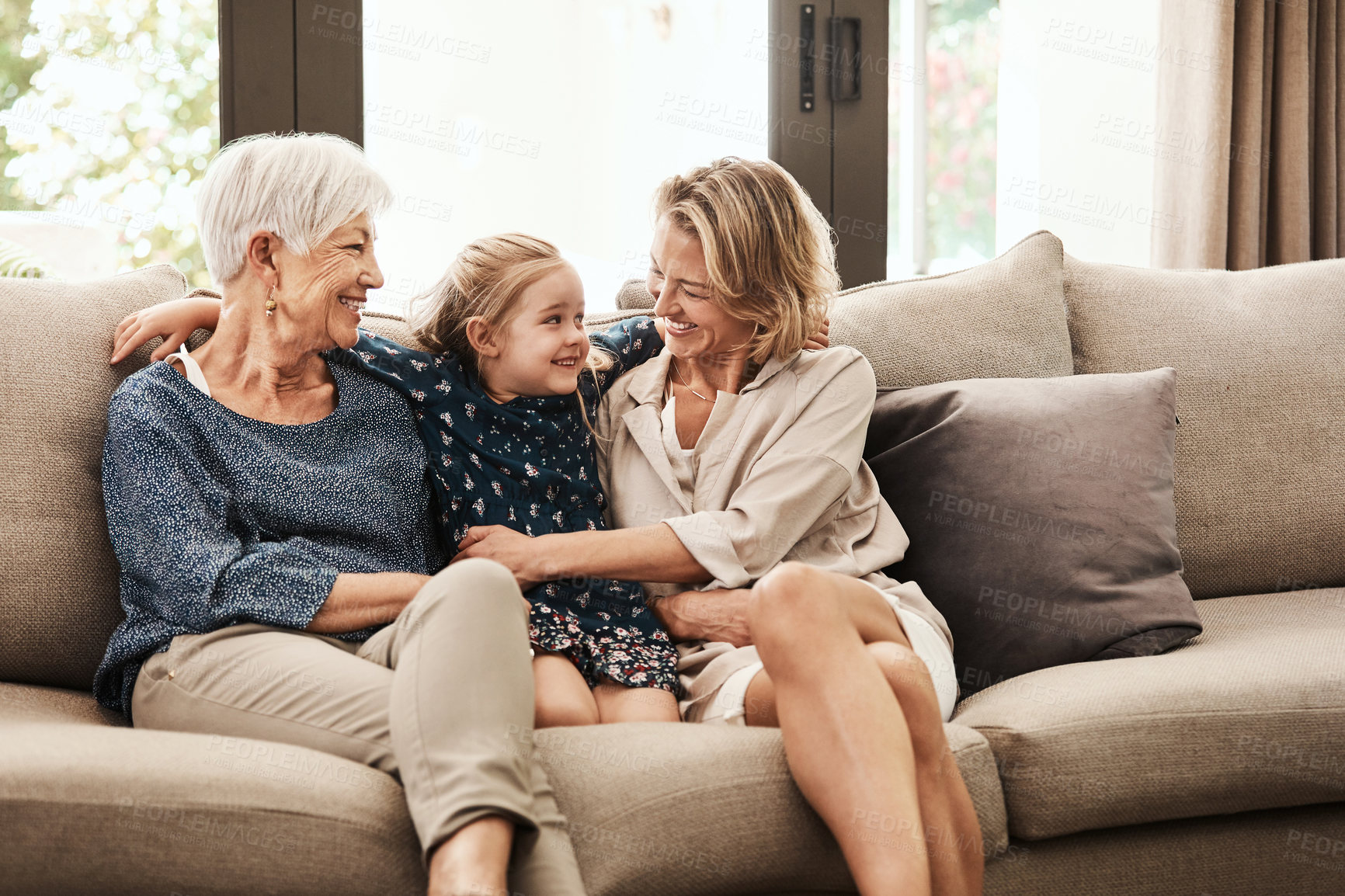 Buy stock photo Shot of a happy senior woman relaxing on the sofa with her daughter and granddaughter at home