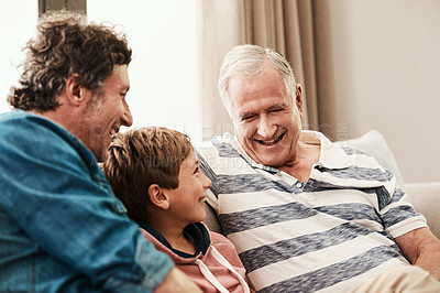 Buy stock photo Shot of an adorable little boy relaxing on the sofa with his father and grandfather at home