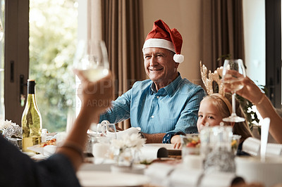 Buy stock photo Cropped shot of a cheerful elderly man having a celebratory toast with his family during Christmas time