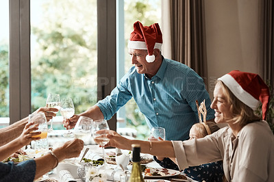 Buy stock photo Cropped shot of a cheerful family having a celebratory toast while having lunch during Christmas time