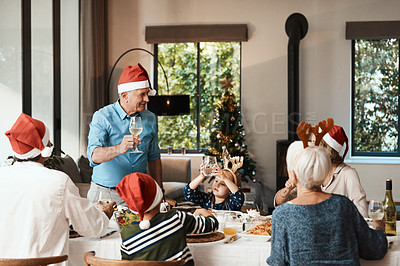 Buy stock photo Cropped shot of a cheerful elderly man making a speech while making a speech with his family at lunch during Christmas time