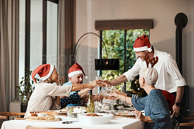 Buy stock photo Cropped shot of a cheerful family having a celebratory toast while having lunch during Christmas time