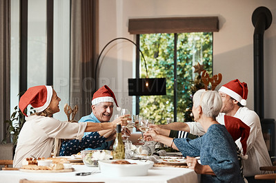 Buy stock photo Cropped shot of a cheerful family having a celebratory toast while having lunch during Christmas time