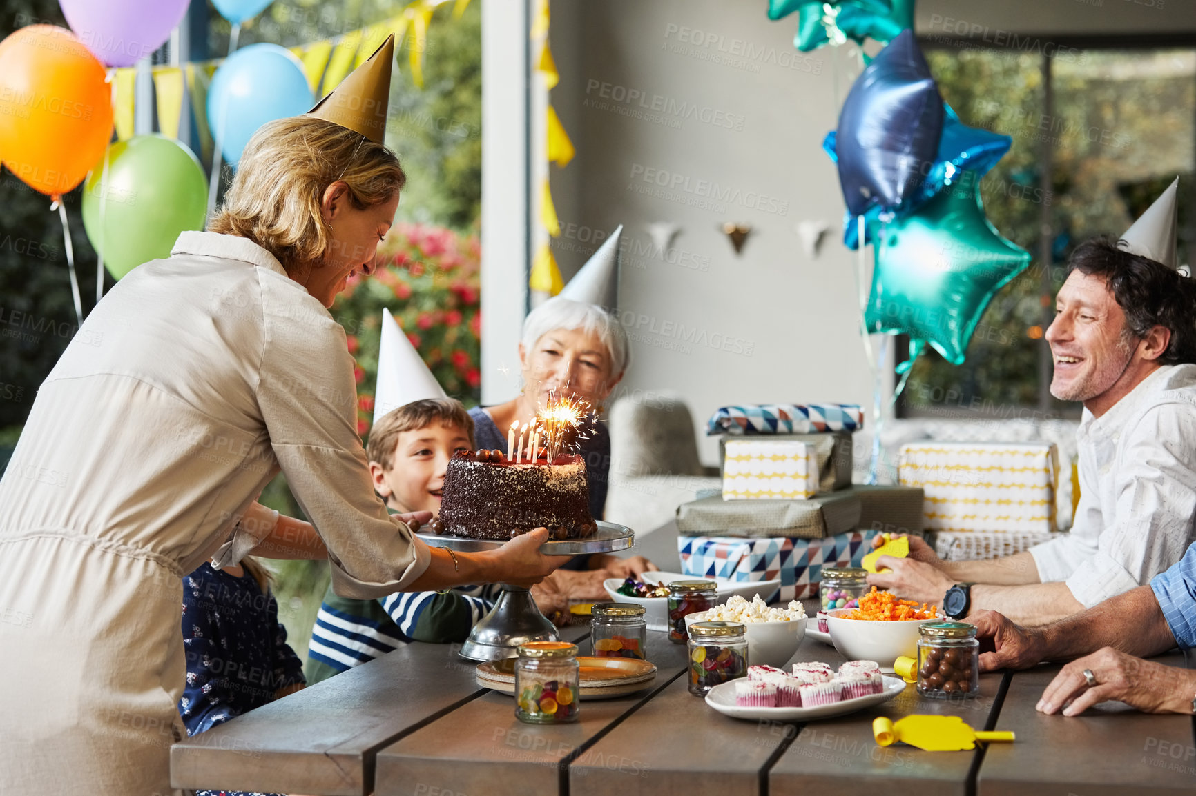 Buy stock photo Birthday cake, outdoor and boy with family, laugh and smile with grandparents on break and together. Parents, home and celebration with dessert, generations and happy people with child in backyard