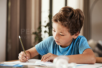 Buy stock photo Shot of a cute little boy doing his homework at home