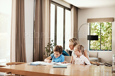 Buy stock photo Shot of a cute little boy doing homework with his mother at home