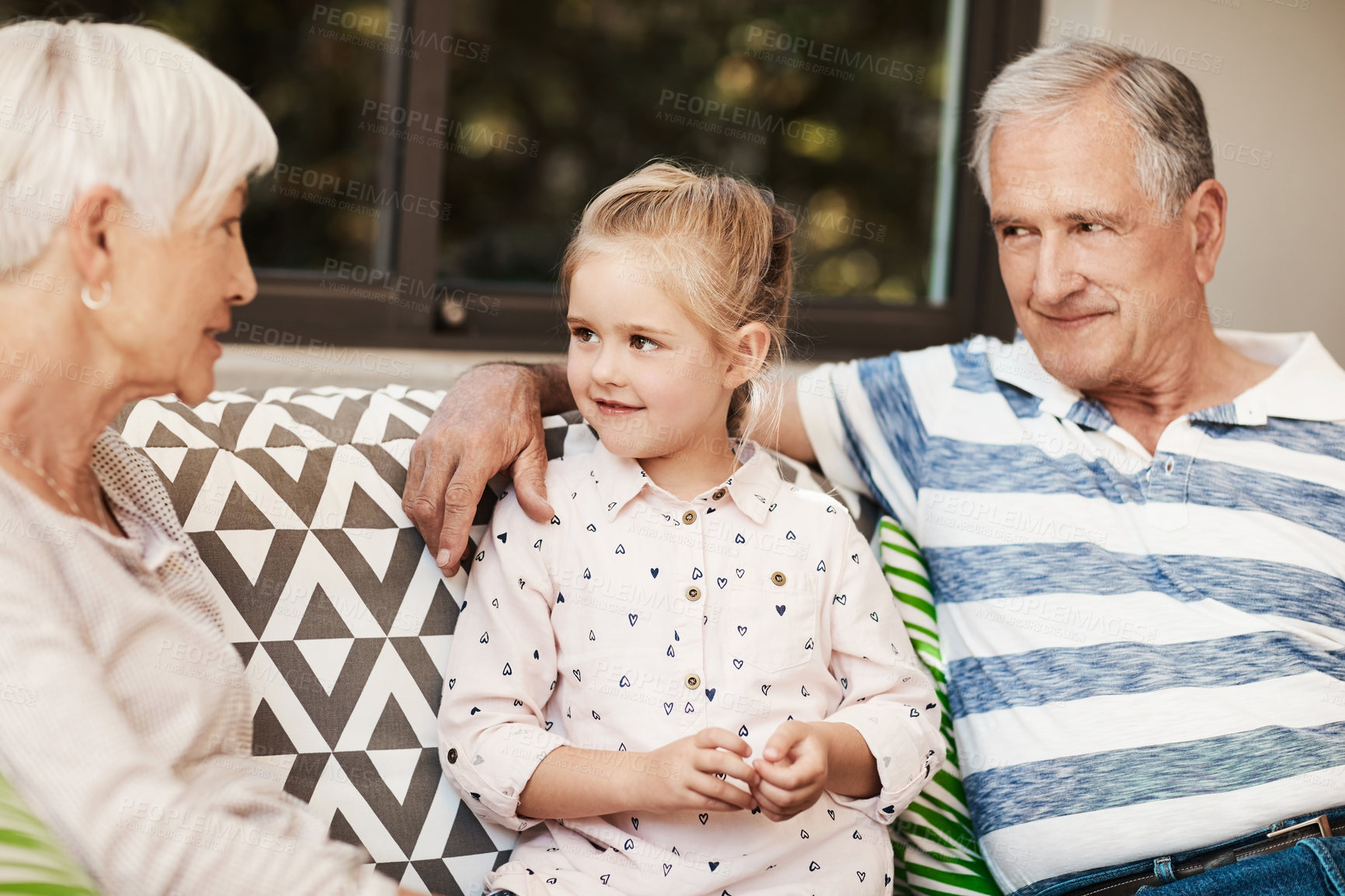 Buy stock photo Grandparents, child and smile with talk on sofa for babysitting weekend, bonding or quality time. Senior family, girl kid and hug on patio with conversation, holiday visit or relationship development