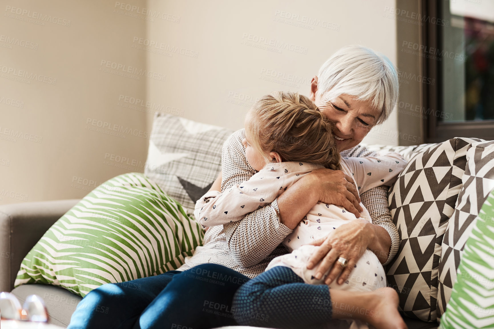 Buy stock photo Grandmother, child and smile with hug on sofa for babysitting weekend, bonding and connection. Happy grandparent, girl and embrace in home with affection, holiday visit and relationship development