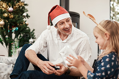 Buy stock photo Cropped shot of a cheerful middle aged man seated with his daughter while she opens a present during Christmas time