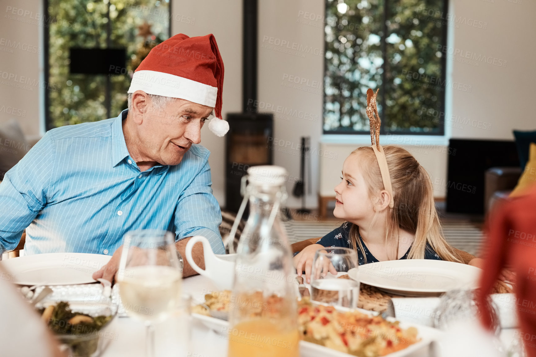 Buy stock photo Christmas, dinner and child with grandpa in home, taking and bonding with girl on December holiday. Xmas, meal and senior man with santa hat, family connection or happy with granddaughter in house