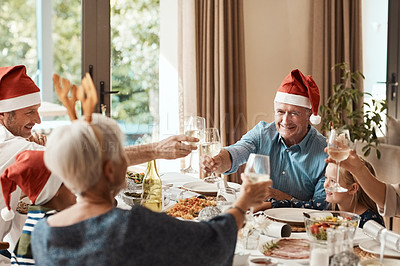 Buy stock photo Cropped shot of a cheerful family having a celebratory toast while having lunch during Christmas time