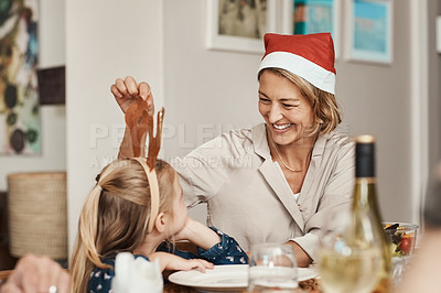 Buy stock photo Cropped shot of a cheerful little girl talking to her mother at a lunch table with family during Christmas time