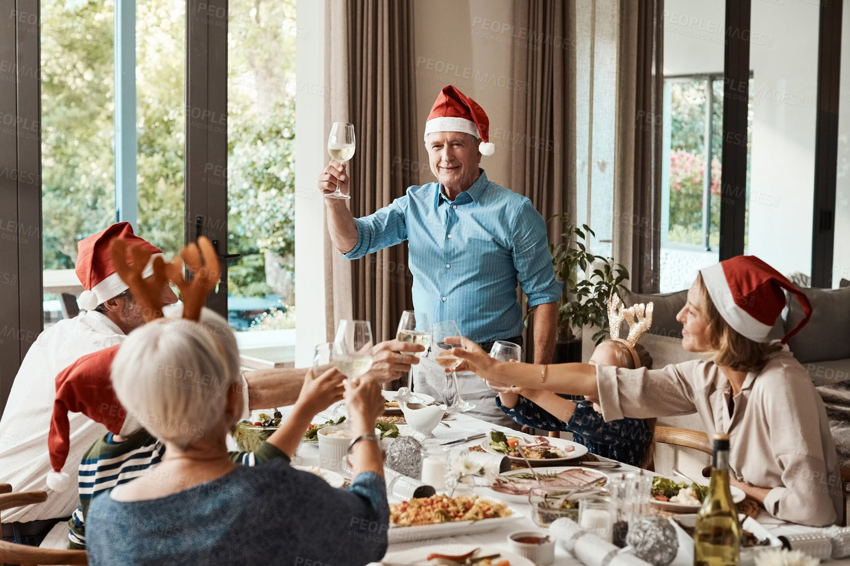 Buy stock photo Cropped shot of a cheerful elderly man making a speech while making a speech with his family at lunch during Christmas time