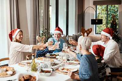 Buy stock photo Cropped shot of a cheerful family having a celebratory toast while having lunch during Christmas time