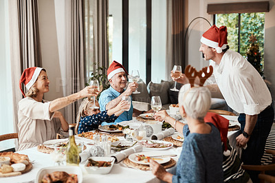 Buy stock photo Cropped shot of a cheerful family having a celebratory toast while having lunch during Christmas time