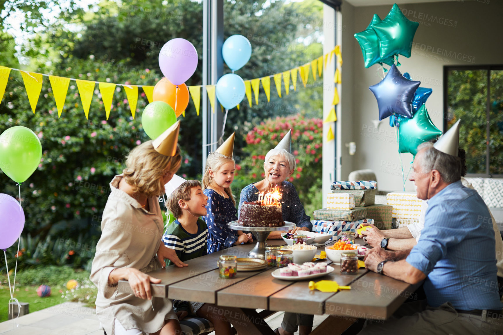 Buy stock photo Shot of a happy family celebrating a birthday at home in the garden