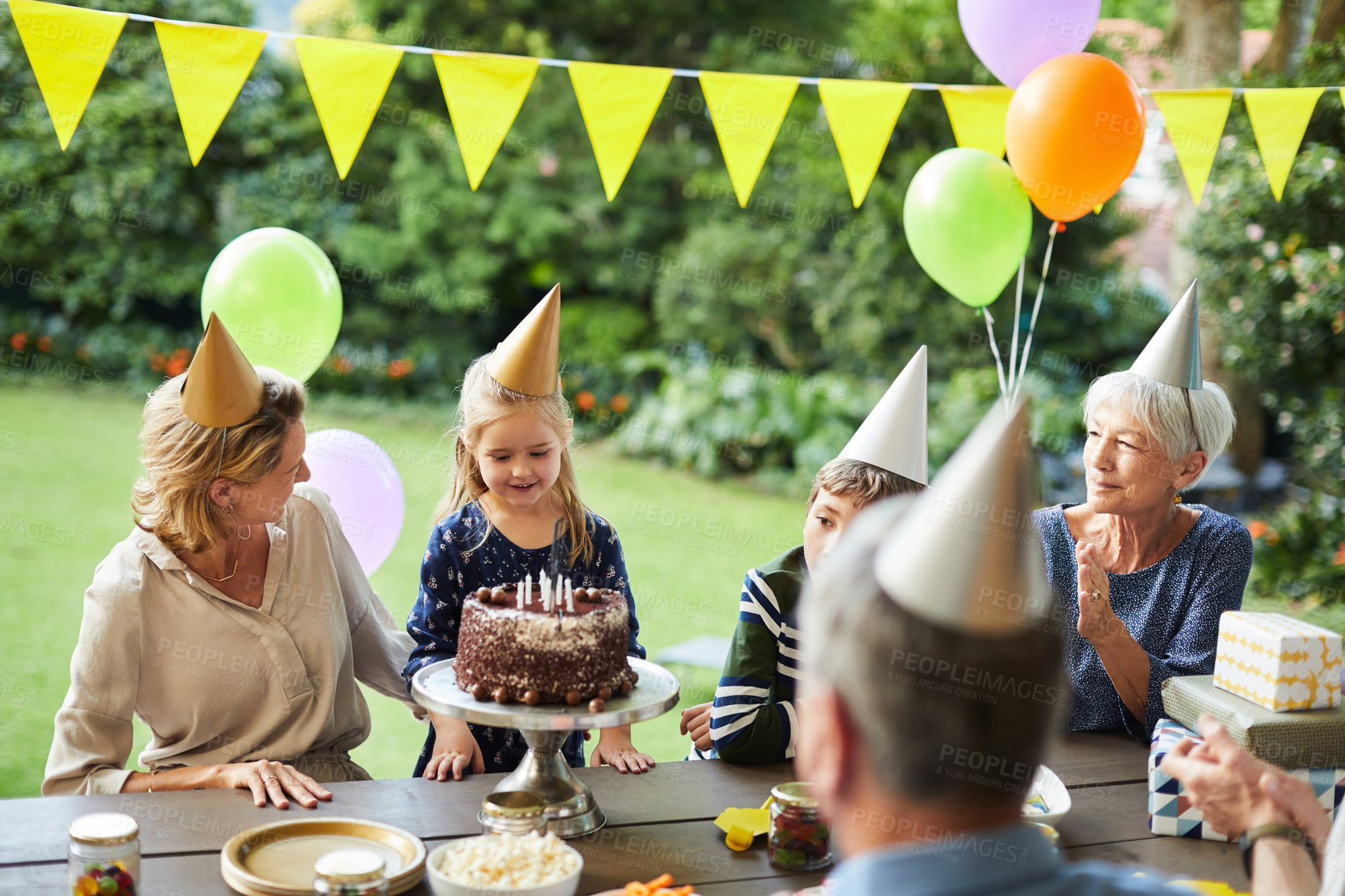 Buy stock photo Birthday cake, outdoor and girl with family, smile and relax with grandparents on break or clapping. Parents, home and celebration with dessert, generations and happy people with children in backyard
