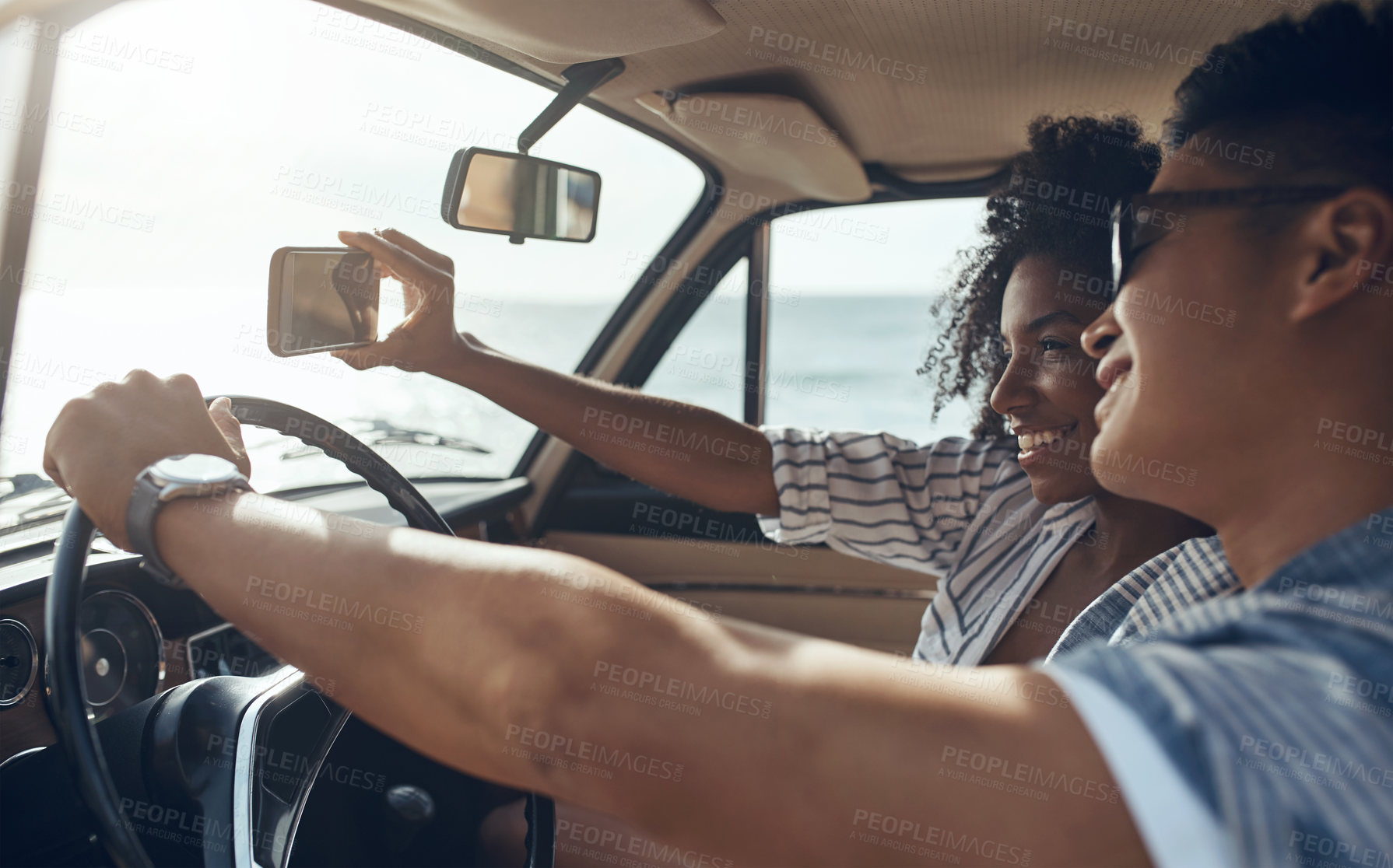 Buy stock photo Shot of a happy young couple taking selfies on a road trip