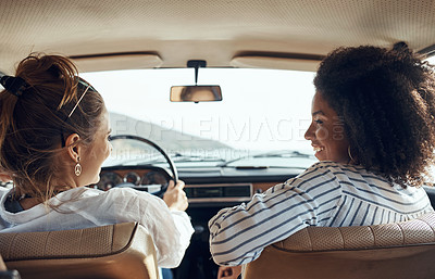 Buy stock photo Shot of a two happy young friends going on a road trip together