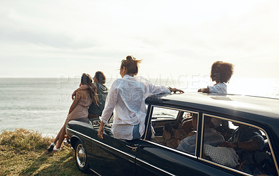Buy stock photo Shot of a group of young friends watching the sunset on a road trip along the coast