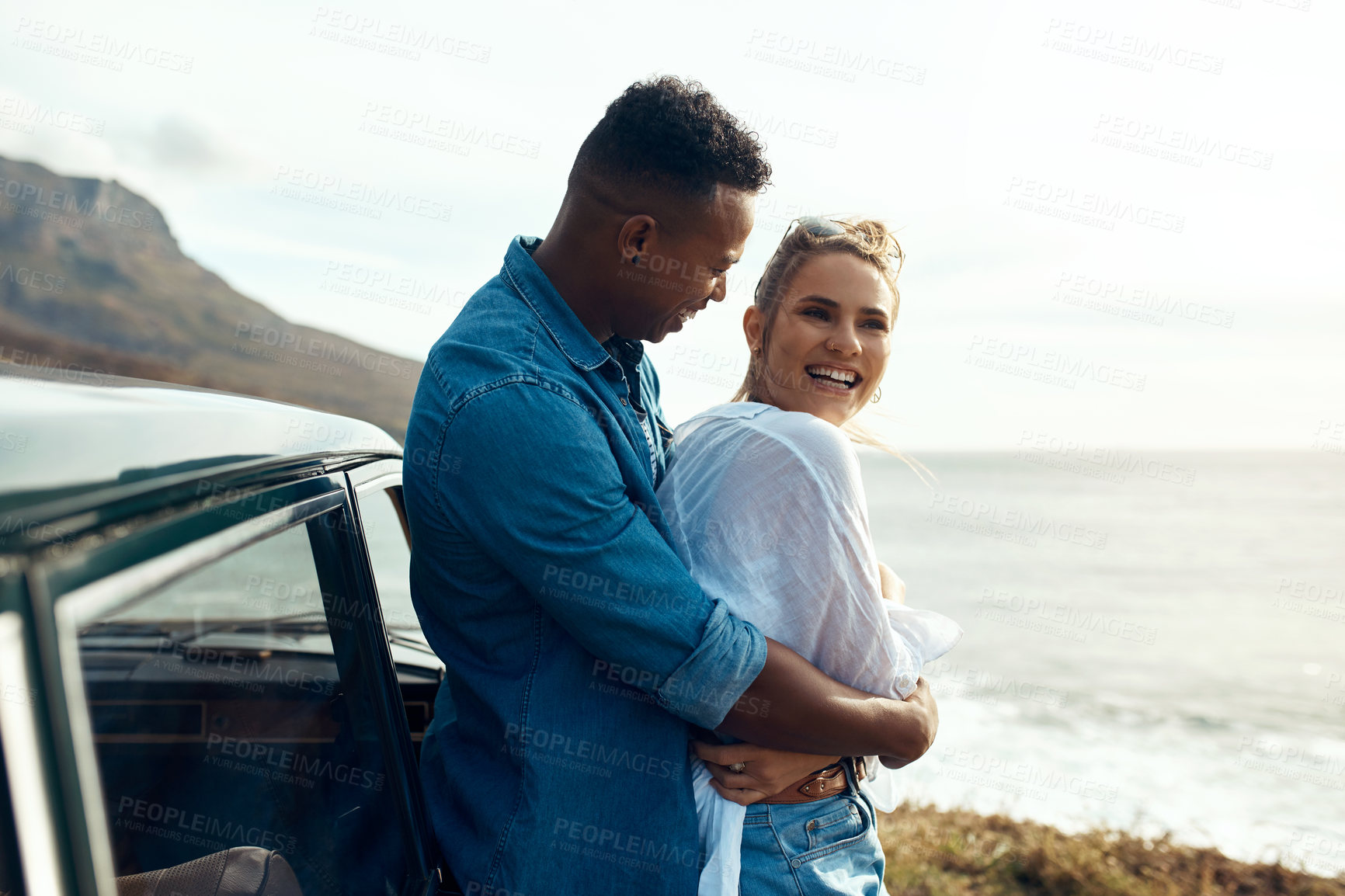 Buy stock photo Shot of a happy young couple sharing a romantic moment on a road trip along the coast