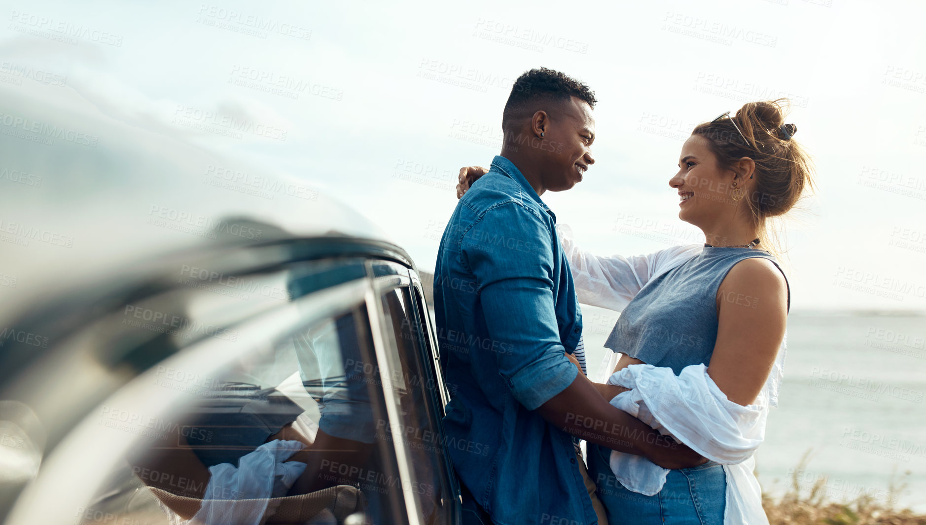 Buy stock photo Shot of a happy young couple sharing a romantic moment on a road trip along the coast