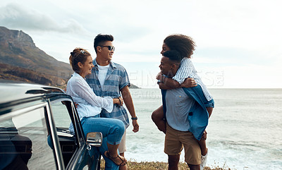 Buy stock photo Shot of a group of happy young friends having fun on a road trip along the coast