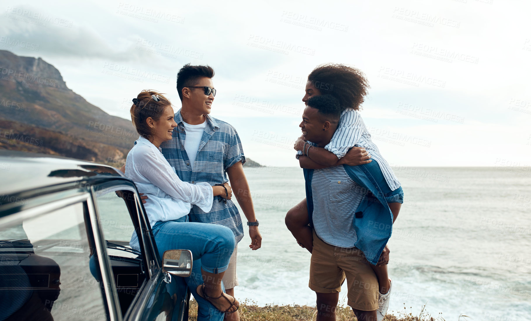 Buy stock photo Shot of a group of happy young friends having fun on a road trip along the coast