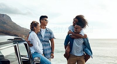 Buy stock photo Shot of a group of happy young friends having fun on a road trip along the coast