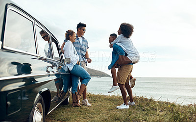 Buy stock photo Shot of a group of happy young friends having fun on a road trip along the coast