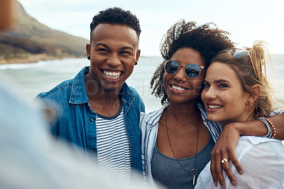 Buy stock photo Shot of a group of happy young friends enjoying a vacation along the coast