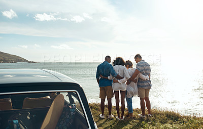 Buy stock photo Shot of a group of young friends watching the sunset on a road trip along the coast