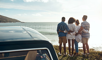 Buy stock photo Shot of a group of young friends watching the sunset on a road trip along the coast