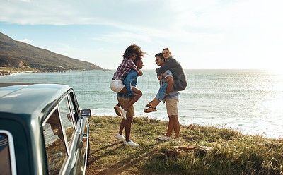 Buy stock photo Shot of a group of happy young friends having fun on a road trip along the coast