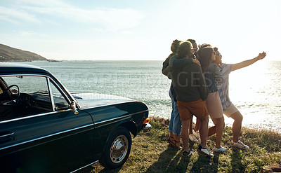 Buy stock photo Shot of a group of happy young friends taking selfies on a road trip along the coast