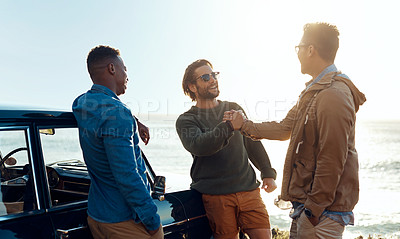 Buy stock photo Shot of happy young friends shaking hands on a road trip along the coast